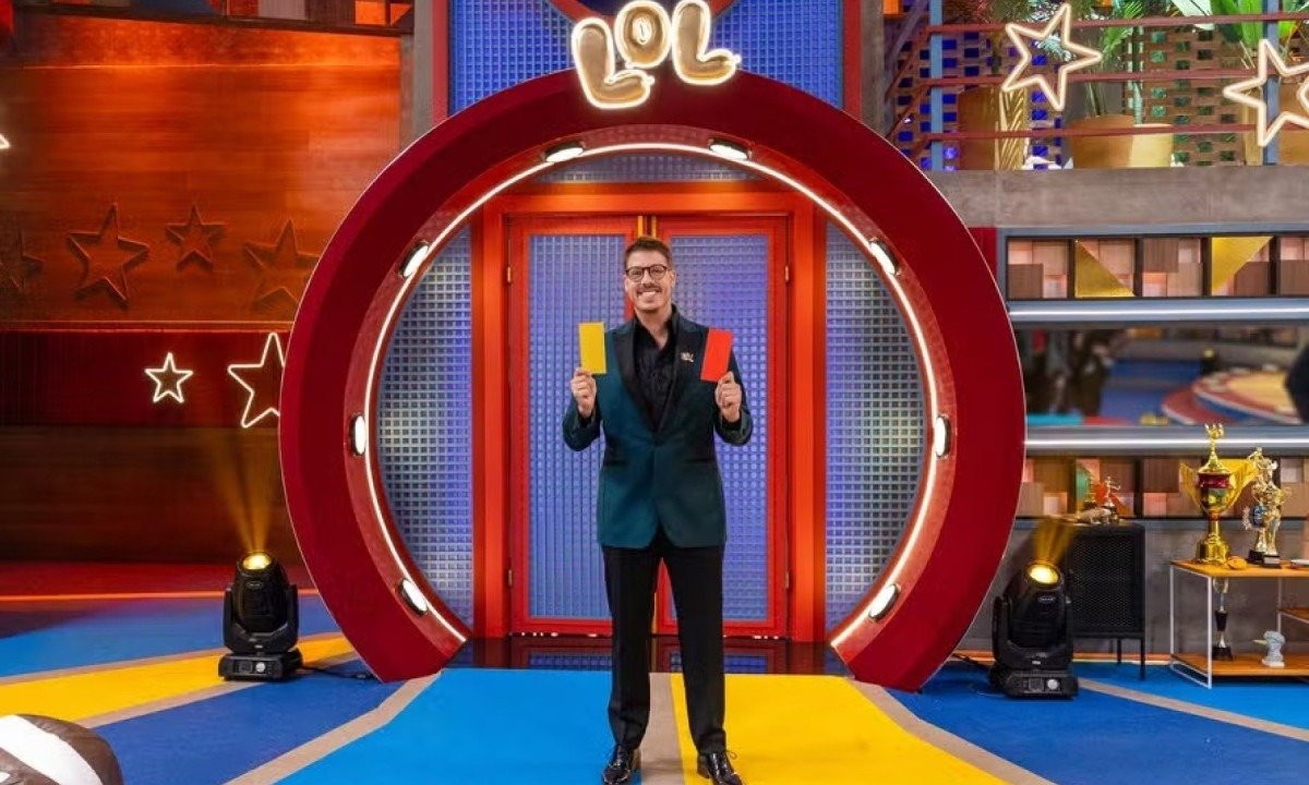 No cen&aacute;rio com v&aacute;rias cores, F&aacute;bio Porchat segura fichas vermelha e amarela ao apresentar o reality LOL: Se rir, j&aacute; era