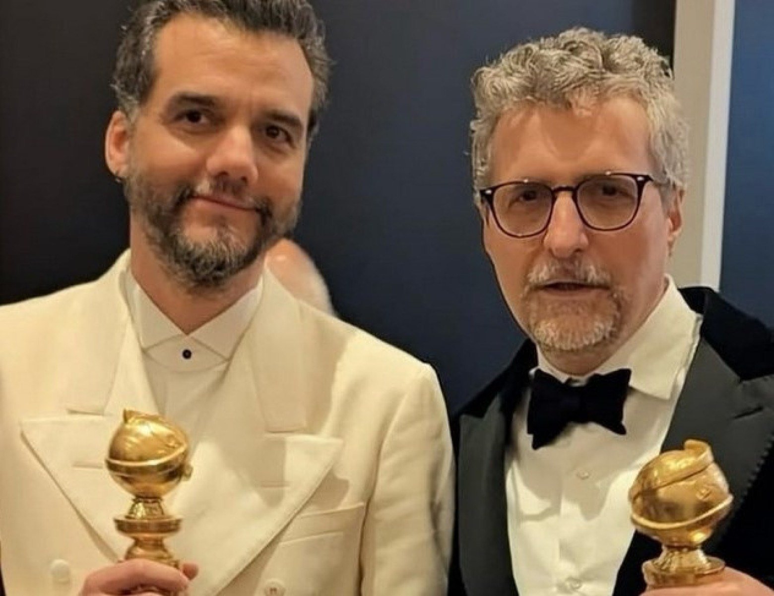  Wagner Moura e Kleber Cavalcante Filho sorriem e seguram trof&eacute;us do Globo de Ouro que receberam em janeiro de 2026