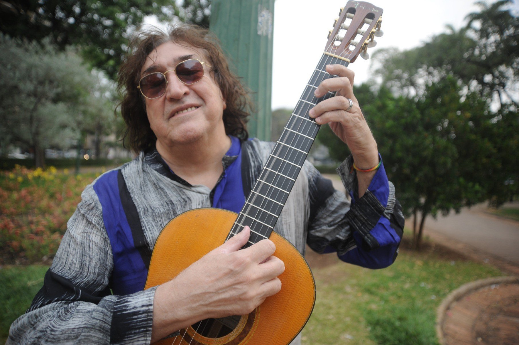   M&uacute;sico Toninho Horta est&aacute; na Pra&ccedil;a da Liberdade, em BH, sorrindo e tocando viol&atilde;o 