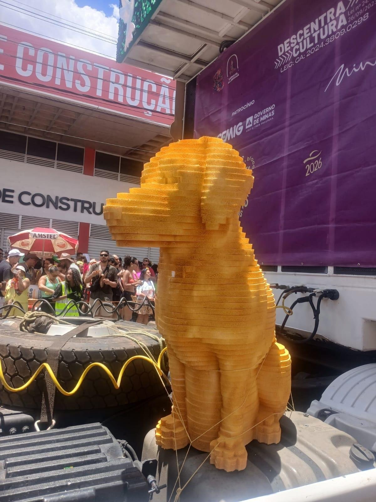 Uma estátua de um cachorro laranja pode ser vista em cima do veículo usado no decorrer do cortejo 