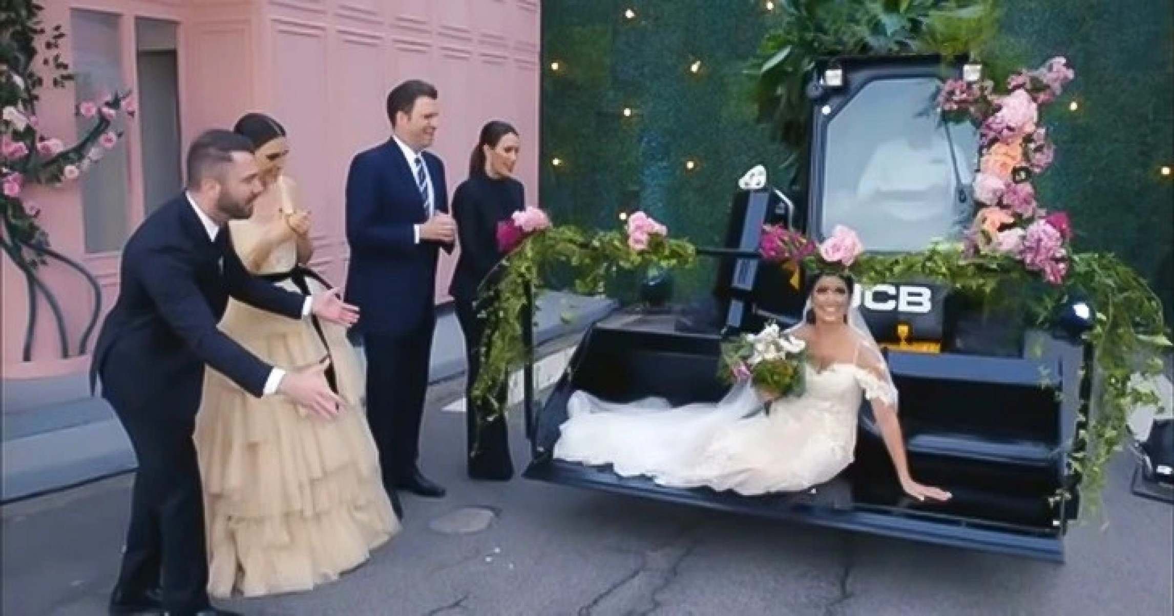  Mulher vestida de noiva sorri, sentada em trator. Ao lado dela h&aacute; convidados com roupa de casamento em cena do programa F&aacute;brica de casamentos, do SBT
