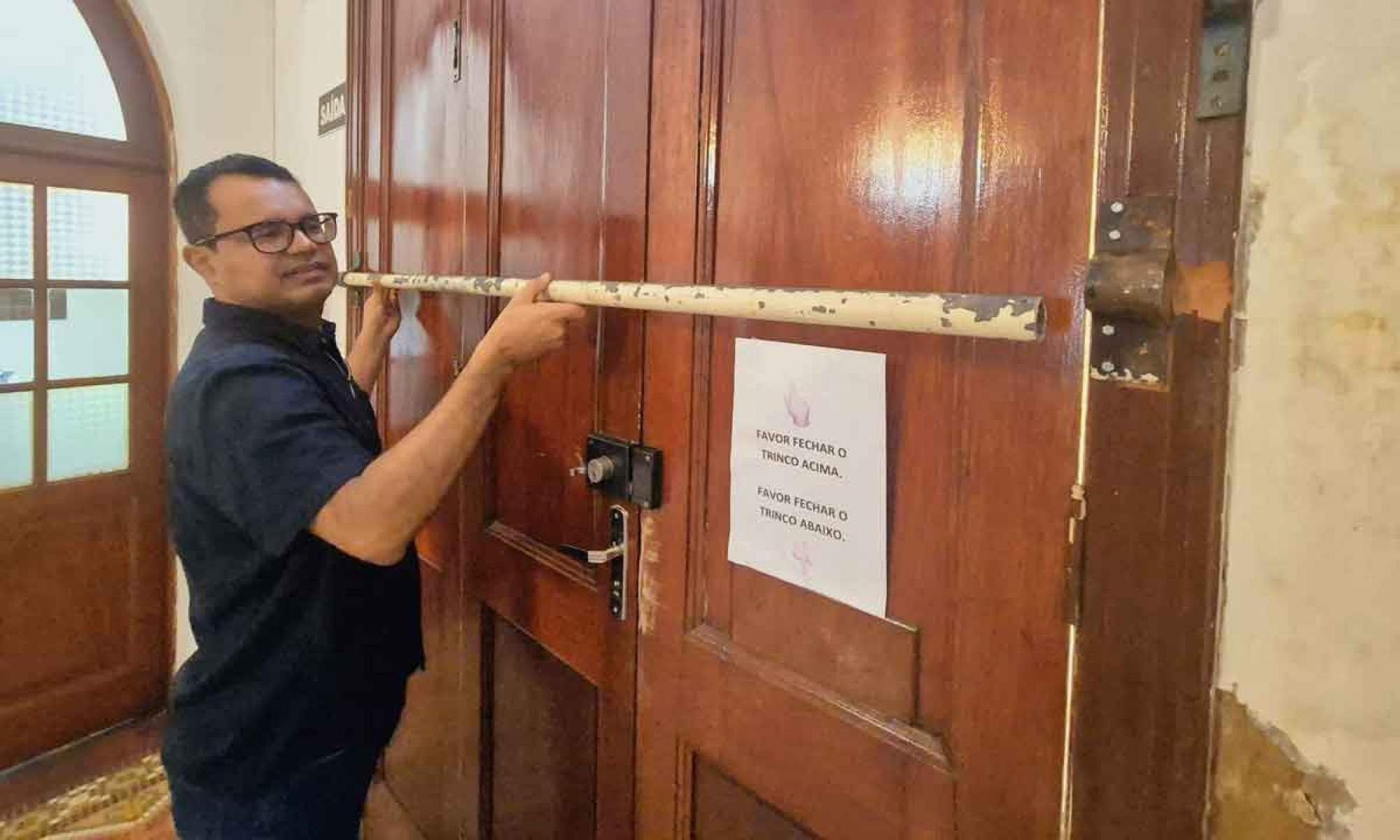 Padre Jos&eacute; J&uacute;nior mostra barra de ferro colocada em porta lateral do santu&aacute;rio depois de invas&atilde;o