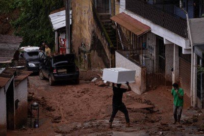 Morador carrega móvel na cabeça em rua enlameada de Juiz de Fora (MG), cidade atormentada pelas chuvas fortes há dias -  (crédito: Eduardo Anizelli/Folhapress)