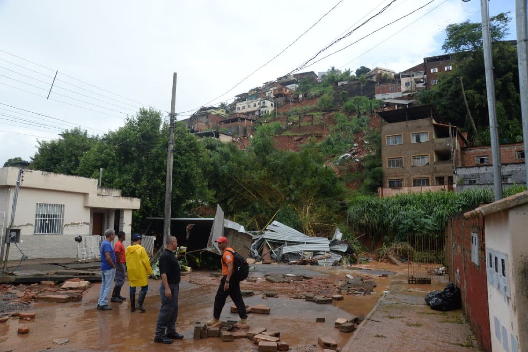 No bairro Jardim Natal, em Juiz de Fora, seis residências foram invadidas pela enchente. Pessoas limpam suas casas, removem móveis e utensílios, máquinas tentam desobstruir o leito do córrego que está repleto de destroços