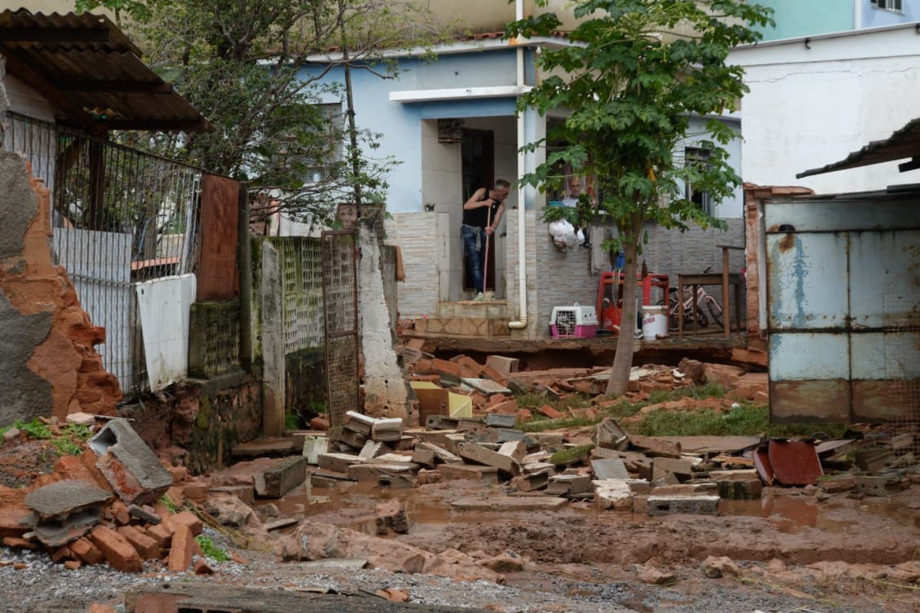 No bairro Jardim Natal, em Juiz de Fora, seis residências foram invadidas pela enchente. Pessoas limpam suas casas, removem móveis e utensílios, máquinas tentam desobstruir o leito do córrego que está repleto de destroços