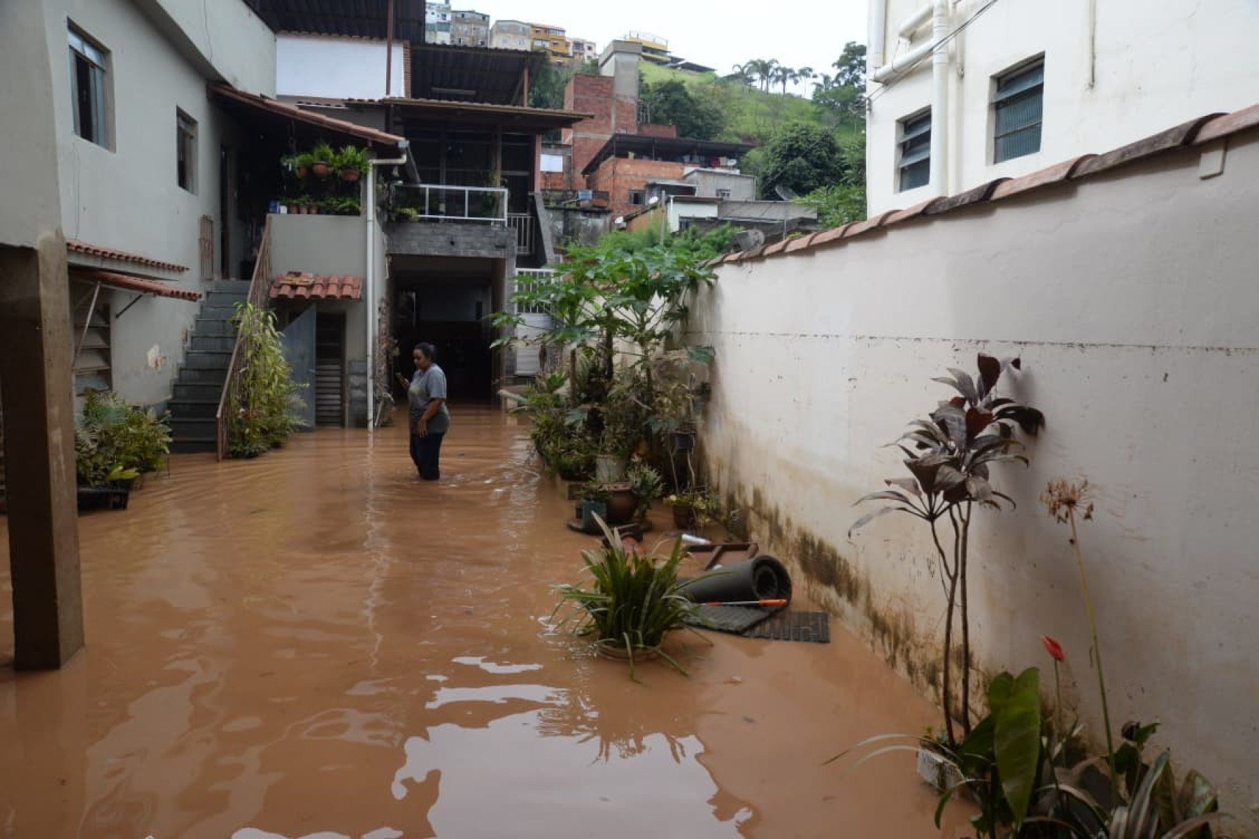 No bairro Jardim Natal, em Juiz de Fora, seis residências foram invadidas pela enchente. Pessoas limpam suas casas, removem móveis e utensílios, máquinas tentam desobstruir o leito do córrego que está repleto de destroços
