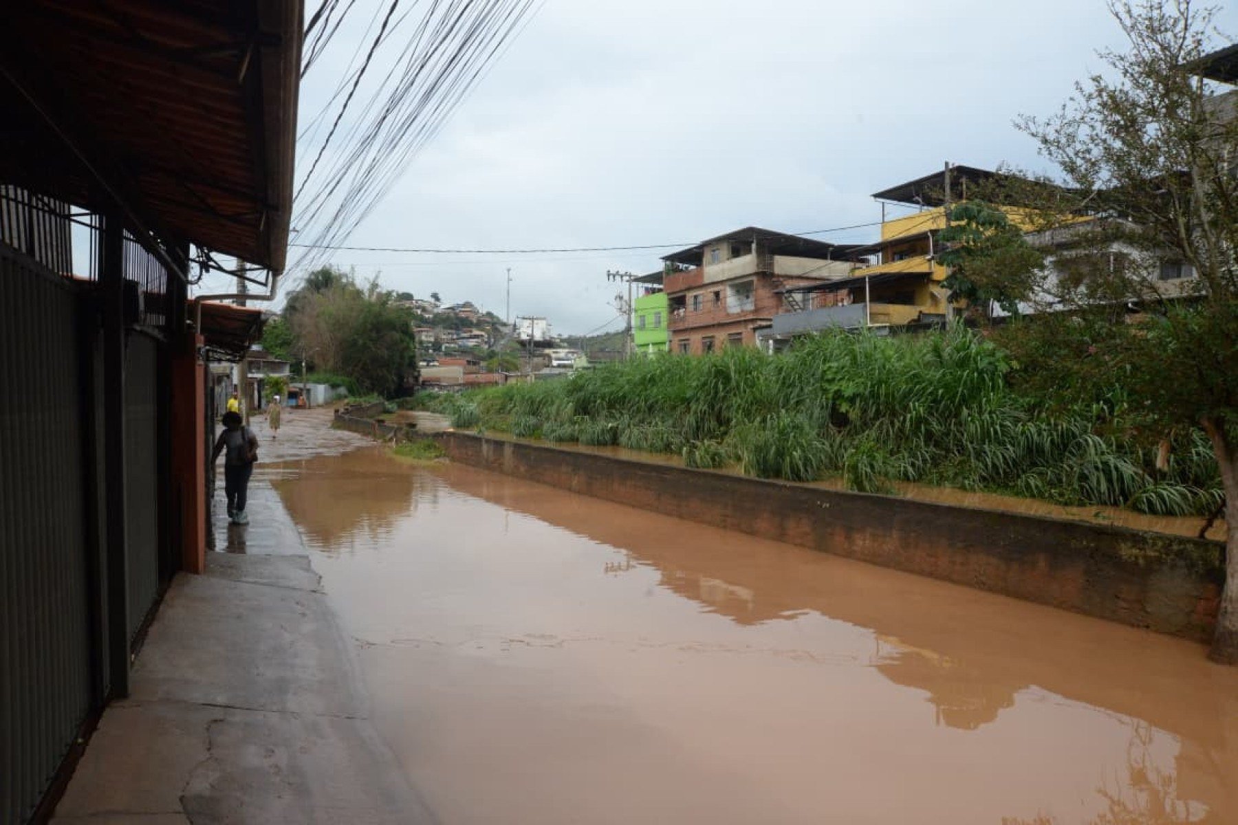 No bairro Jardim Natal, em Juiz de Fora, seis residências foram invadidas pela enchente. Pessoas limpam suas casas, removem móveis e utensílios, máquinas tentam desobstruir o leito do córrego que está repleto de destroços