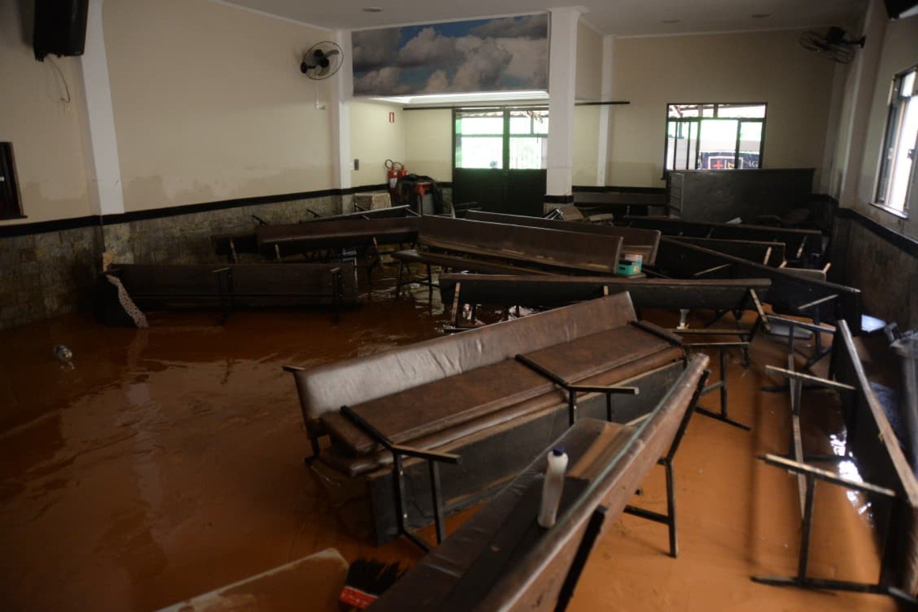 No bairro Jardim Natal, em Juiz de Fora, seis residências foram invadidas pela enchente. Pessoas limpam suas casas, removem móveis e utensílios, máquinas tentam desobstruir o leito do córrego que está repleto de destroços