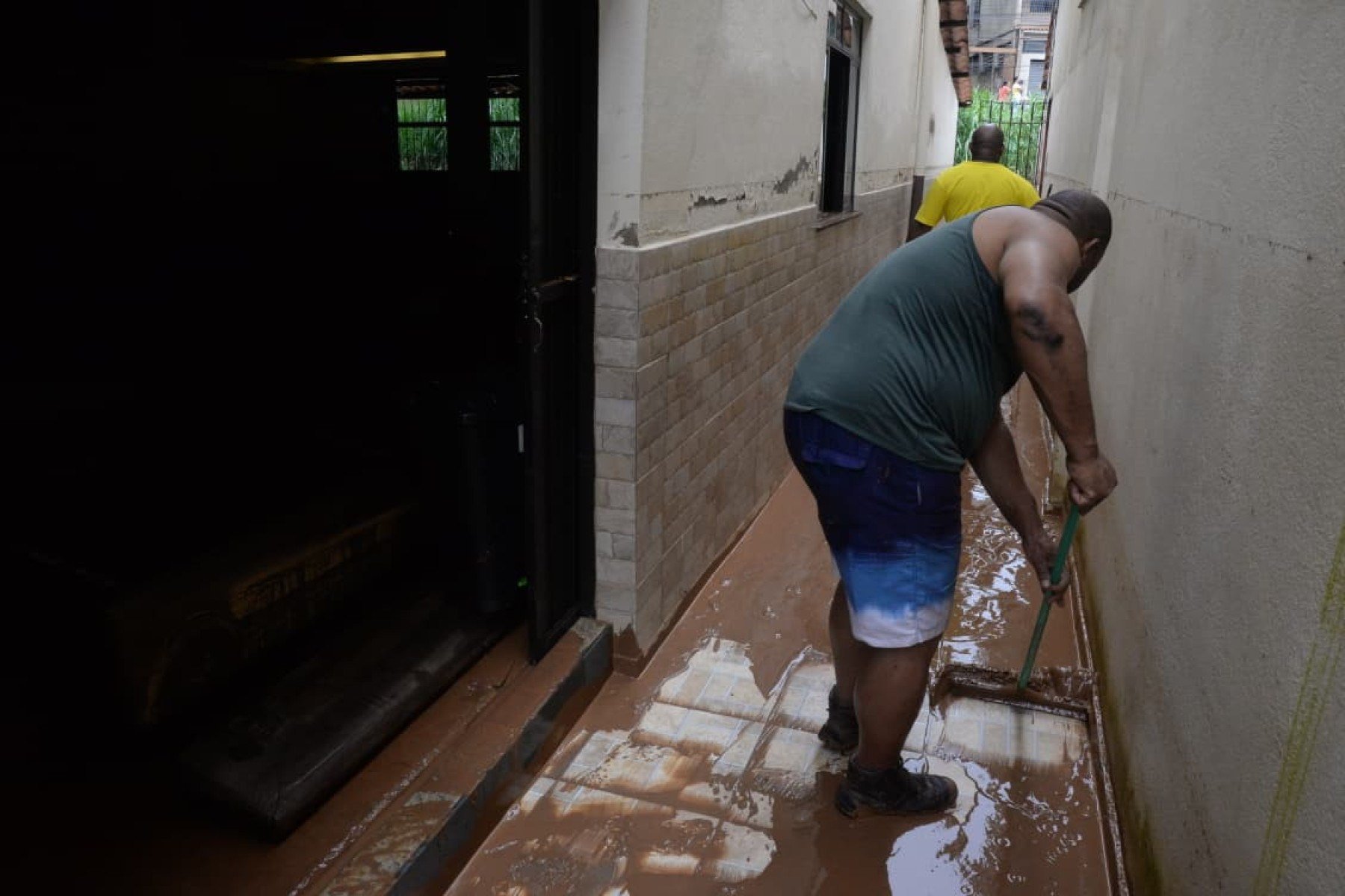 No bairro Jardim Natal, em Juiz de Fora, seis residências foram invadidas pela enchente. Pessoas limpam suas casas, removem móveis e utensílios, máquinas tentam desobstruir o leito do córrego que está repleto de destroços