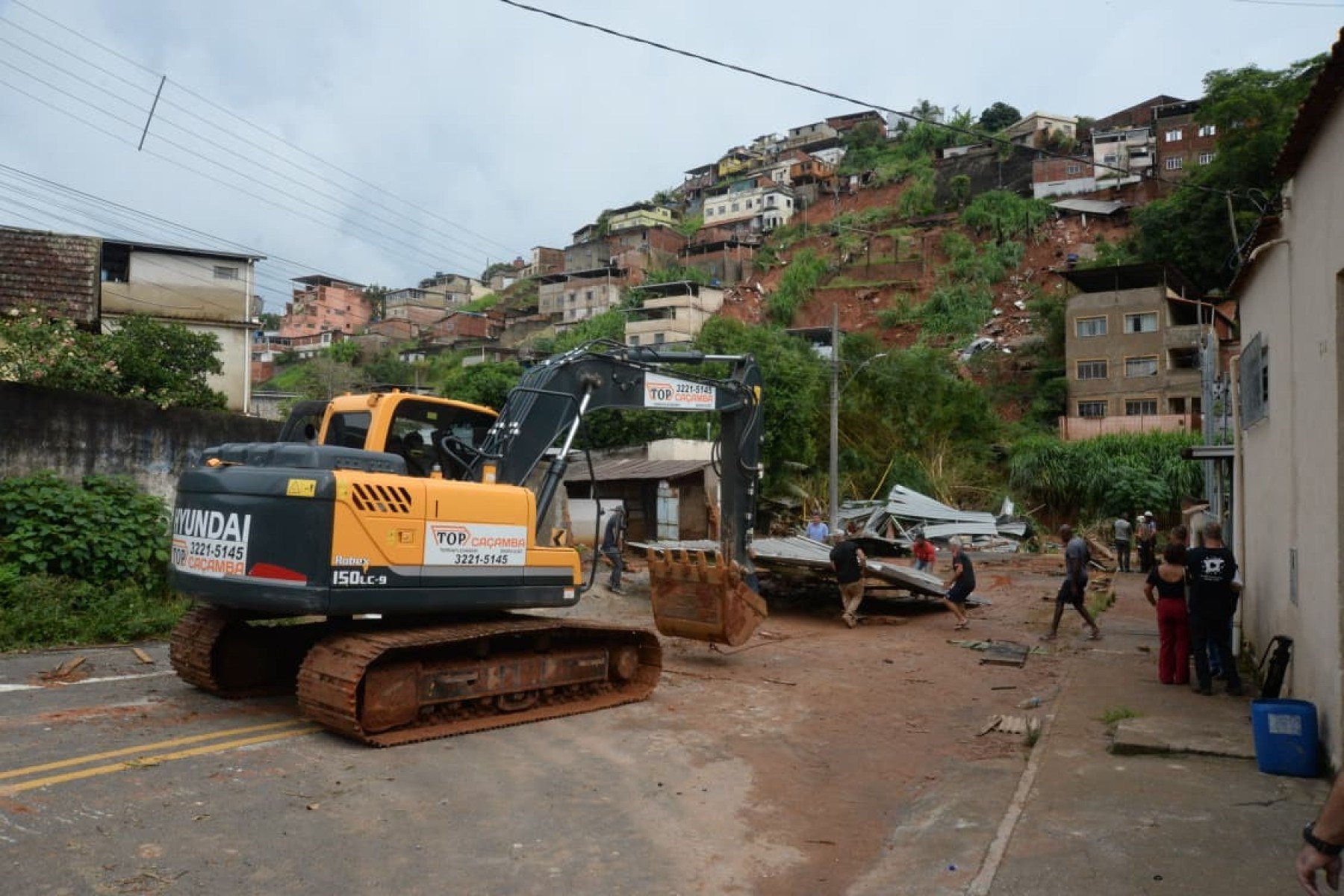 No bairro Jardim Natal, em Juiz de Fora, seis residências foram invadidas pela enchente. Pessoas limpam suas casas, removem móveis e utensílios, máquinas tentam desobstruir o leito do córrego que está repleto de destroços