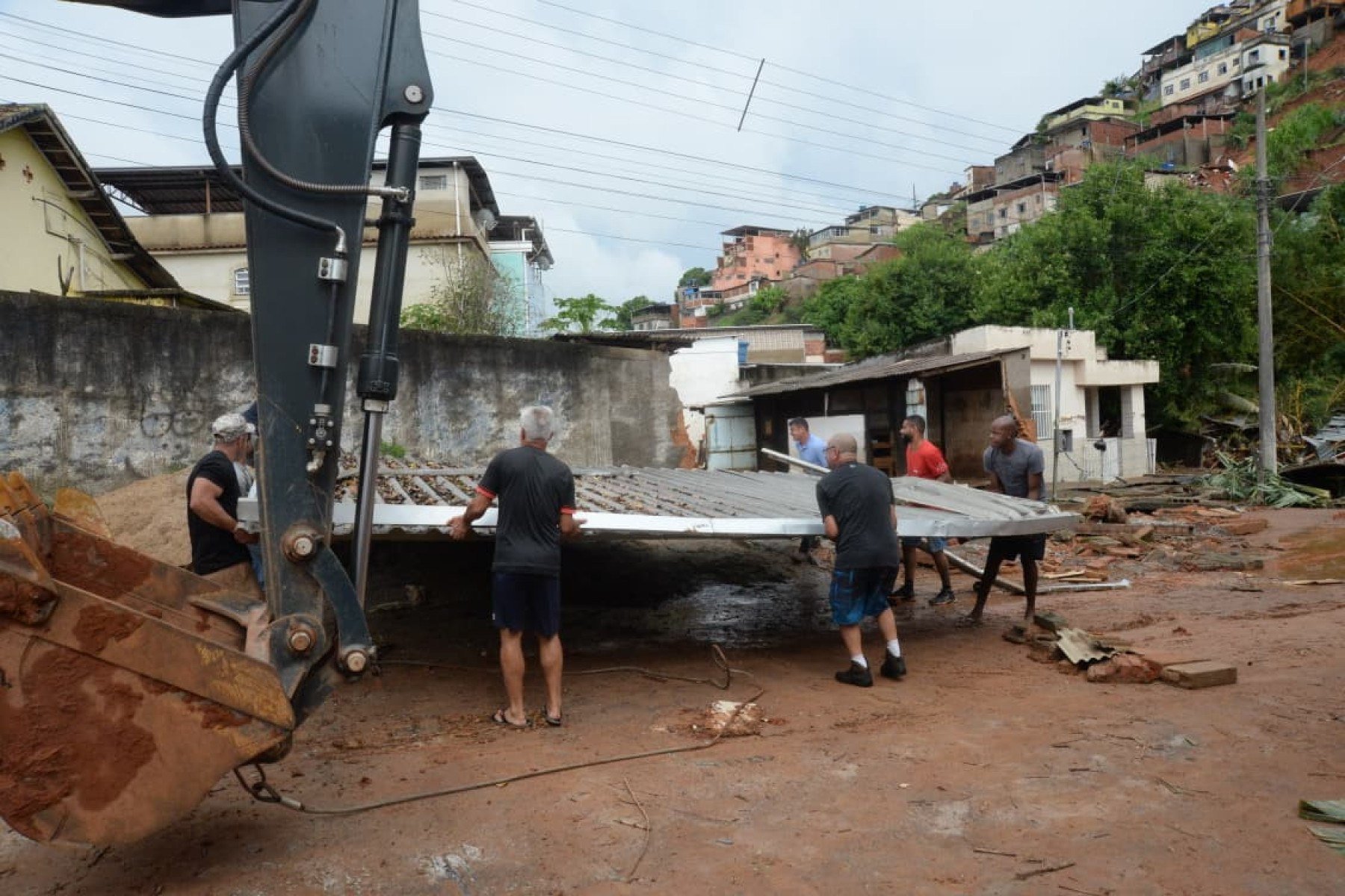 No bairro Jardim Natal, em Juiz de Fora, seis residências foram invadidas pela enchente. Pessoas limpam suas casas, removem móveis e utensílios, máquinas tentam desobstruir o leito do córrego que está repleto de destroços