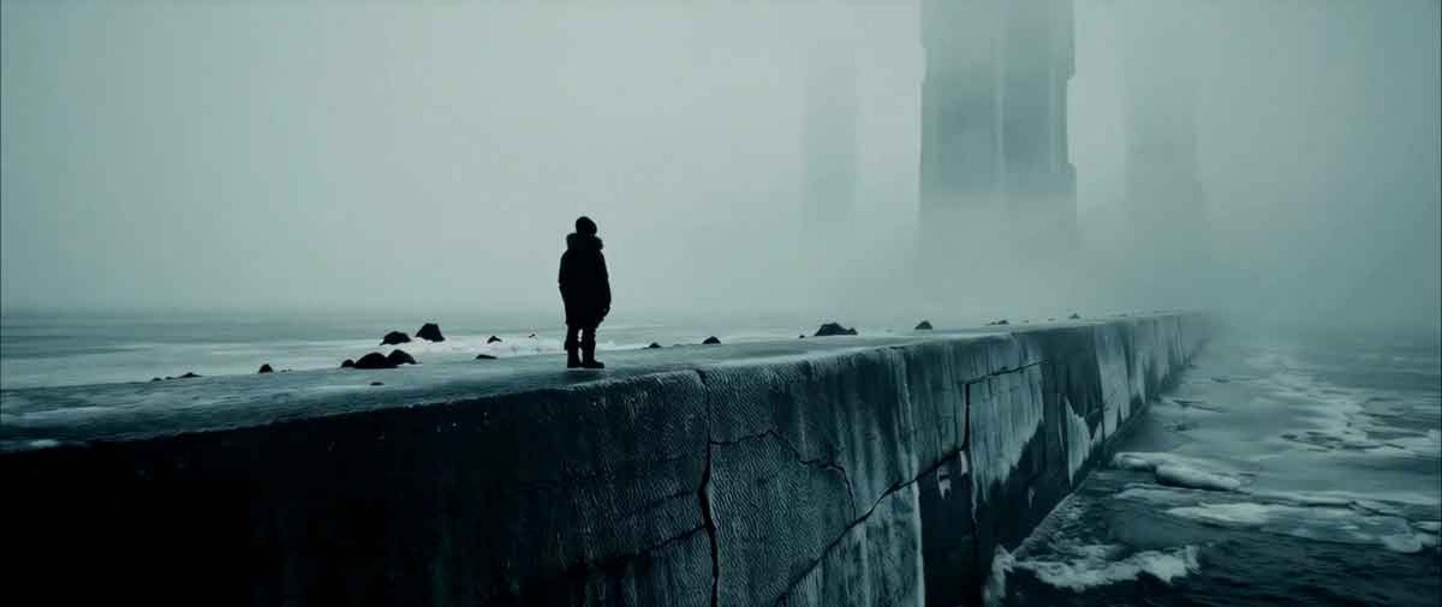 Cena do filme The gardner of ashes mostra homem solitário sob o céu cinzento em pier marítimo