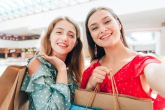 Clientes sorridentes com sacolas de compras; empreendedores precisam entender a importância do custo de aquisição de um cliente -  (crédito: Freepik)