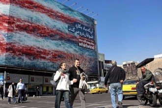 Pessoas caminham em frente a um outdoor anti-EUA instalado em um prédio em uma rua de Teerã, em 26 de fevereiro de 2026 -  (crédito: AFP)