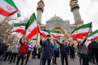 Manifestantes se reúnem com bandeiras nacionais iranianas durante um protesto em apoio ao governo e contra os ataques dos EUA e de Israel em frente a uma mesquita em Teerã -  (crédito: ATTA KENARE / AFP)