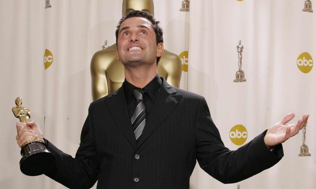 Cantor e compositor uruguaio Jorge Drexler sorri e olha para cima, com os bra&ccedil;os abertos, e segura o Oscar de Melhor Can&ccedil;&atilde;o Original que ganhou em 2005 com o tema do filme 'Di&aacute;rios de motocicleta'