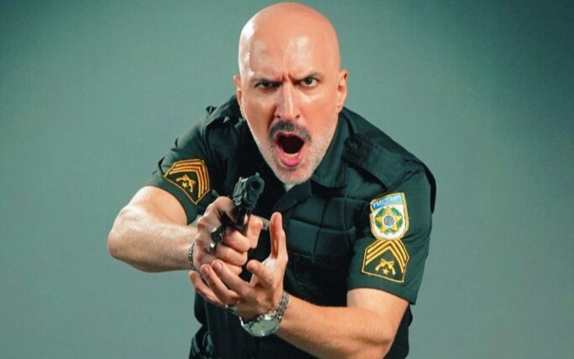 ntonio Tabet aponta rev&oacute;lver para a c&acirc;mera e grita, caracterizado como o policial Pe&ccedil;anha