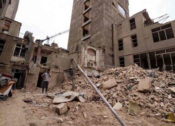 Iraniano conversa ao telefone em frente de prédios destruídos em Teerã, capital da nação persa -  (crédito: Atta Kenare/AFP)