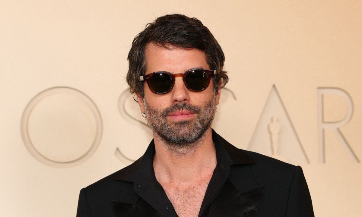 Usando &oacute;culos escuros, o paulista Adolpho Veloso, que concorreu ao Oscar de Melhor Fotografia, posa para os fot&oacute;grafos ao chegar ao Teatro Dolby, em Los Angeles