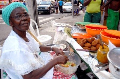 <p>Mais que culinária, a Baiana do Acarajé é símbolo da resistência afro-brasileira. Sua história entrelaça fé, ancestralidade e luta pela liberdade, visto que os bolinhos de feijão com dendê financiaram terreiros e cartas de alforria. Assim, ser baiana do acarajé é profissão centenária, feminina e sagrada, concedida pelos orixás.</p>
 -  (crédito: wikimedia commons Rodrigues Pozzebom)