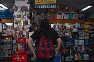 Uma mulher compra um pacote de cannabis recreativa em uma farmácia em Montevidéu, em 18 de março de 2026 -  (crédito: Foto por EITAN ABRAMOVICH / AFP)