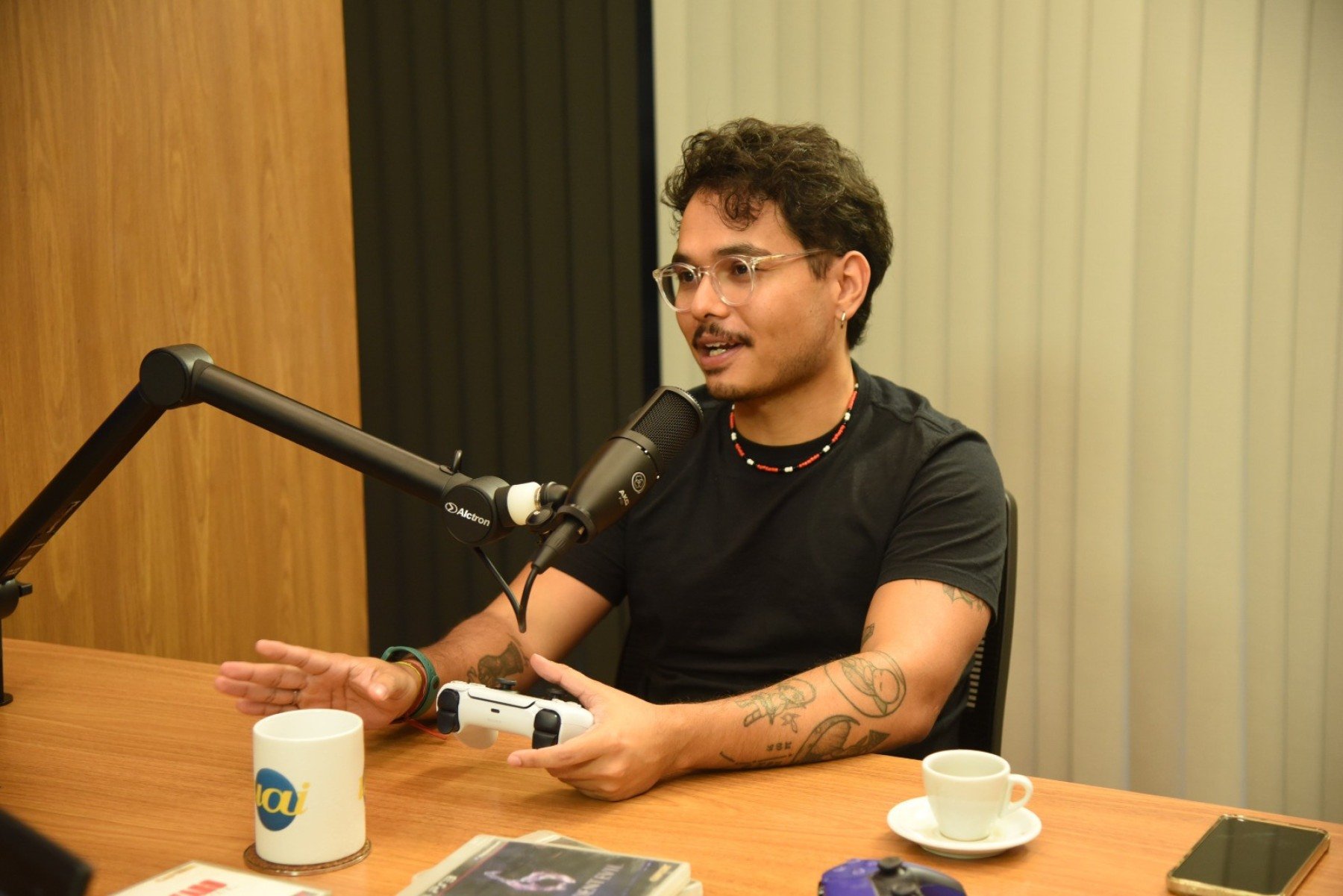 Leo Lima, apresentador do Glitch Clube, e o convidado Jo&atilde;o Alves gravam epis&oacute;dio em est&uacute;dio enquanto Resident Evil Requiem &eacute; exibido na TV ao fundo