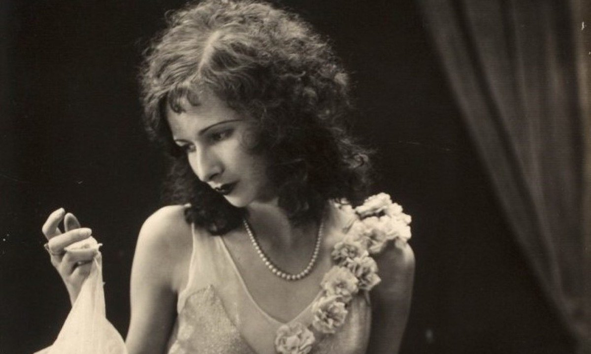 A jovem Eva Nil, estrela do cinema brasileiro dos anos 1920, olha para o lado e usa vestido branco decotado