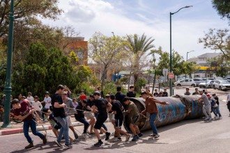 Crianças removem parte de um fragmento de míssil iraniano que caiu no pátio de uma escola no assentamento israelense de Peduel, na Cisjordânia ocupada, em 23 de março de 2026 -  (crédito: MAYA LEVIN / AFP)