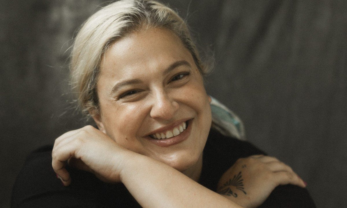 Cantora Alice Caymmi tem as m&atilde;os cruzadas sobre os ombros e sorri para a c&acirc;mera