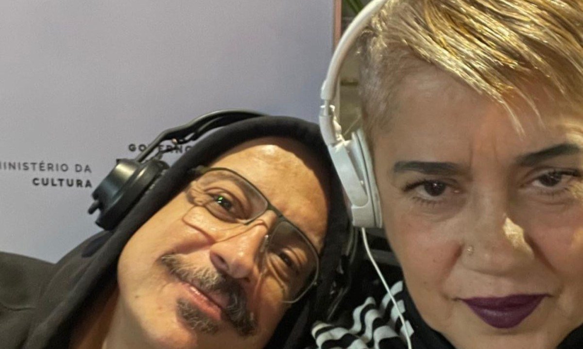 DJ Fausto est&aacute; deitado no ombro da DJ Sandra e os dois olham para a c&acirc;mera