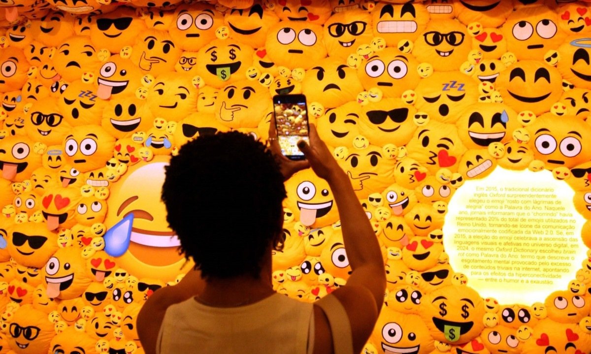 Visitante ergue os bra&ccedil;os e fotografa espa&ccedil;o da exposi&ccedil;&atilde;o dedicada a memes, repleto de carinhas amarelas divertidas