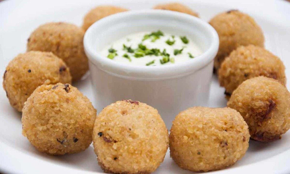 Bolinhos de arroz dispostos em prato redondo, com potinho de molho no meio  