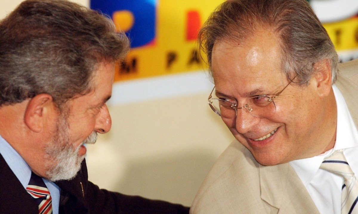 Lula e Jos&eacute; Dirceu conversam, um olhando para o outro, e sorriem