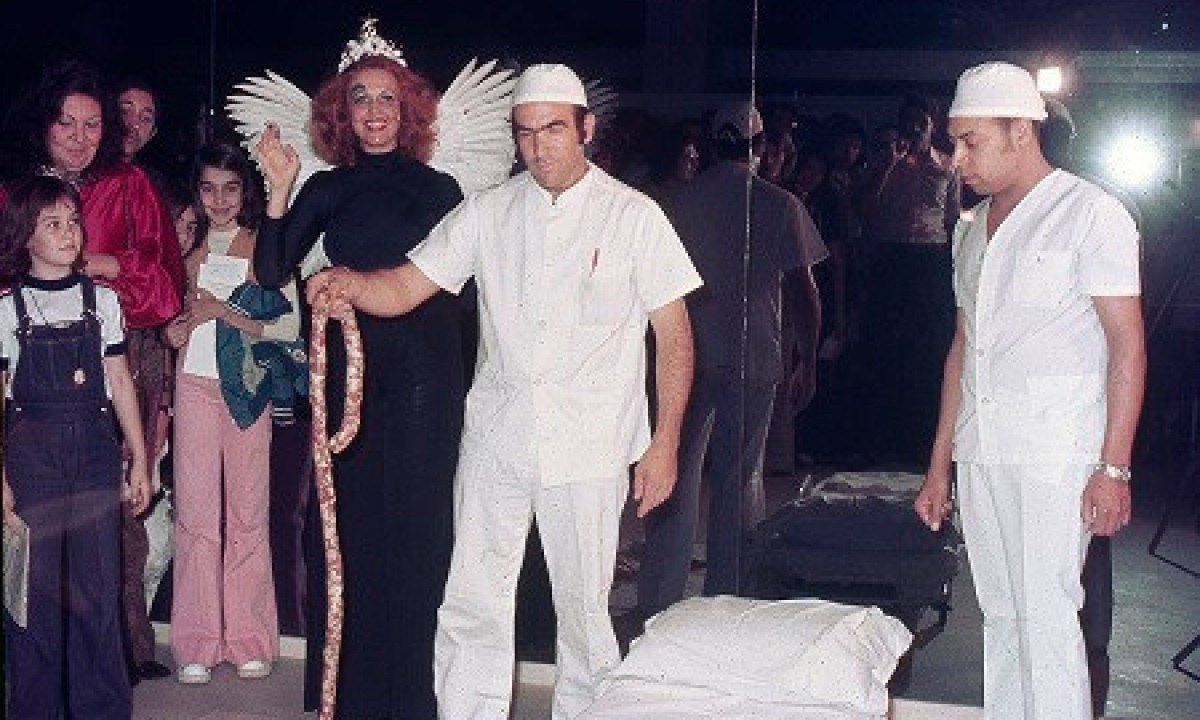 A artista Teresinha Soares vestida de anjo, ao lado de integrantes de uma performance com elementos como queijo e lingui&ccedil;a, no sagu&atilde;o do Pal&aacute;cio das Artes 