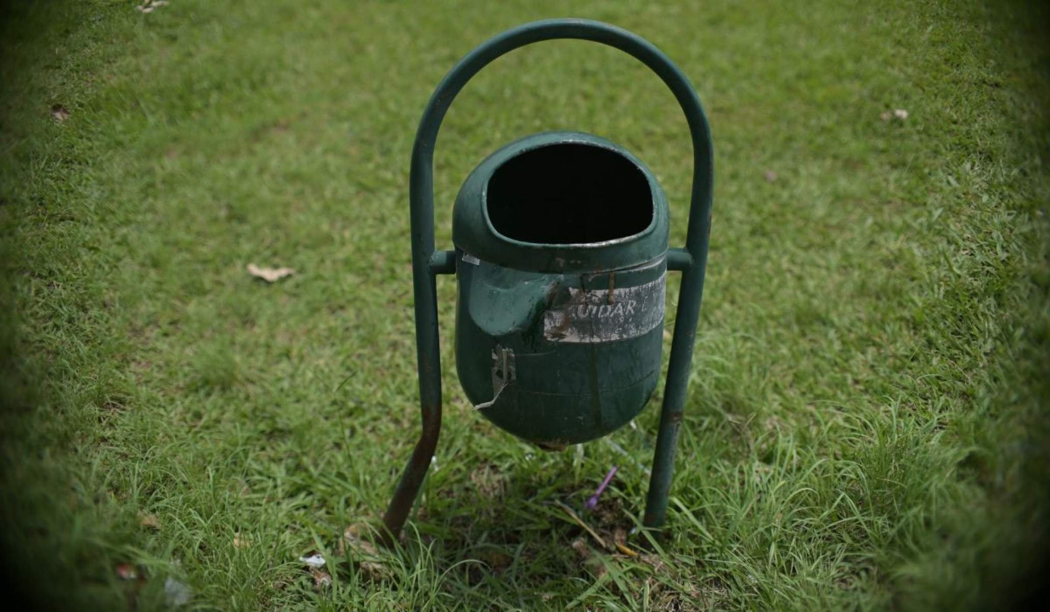 Na foto, uma lixeira amassada e enferrujada