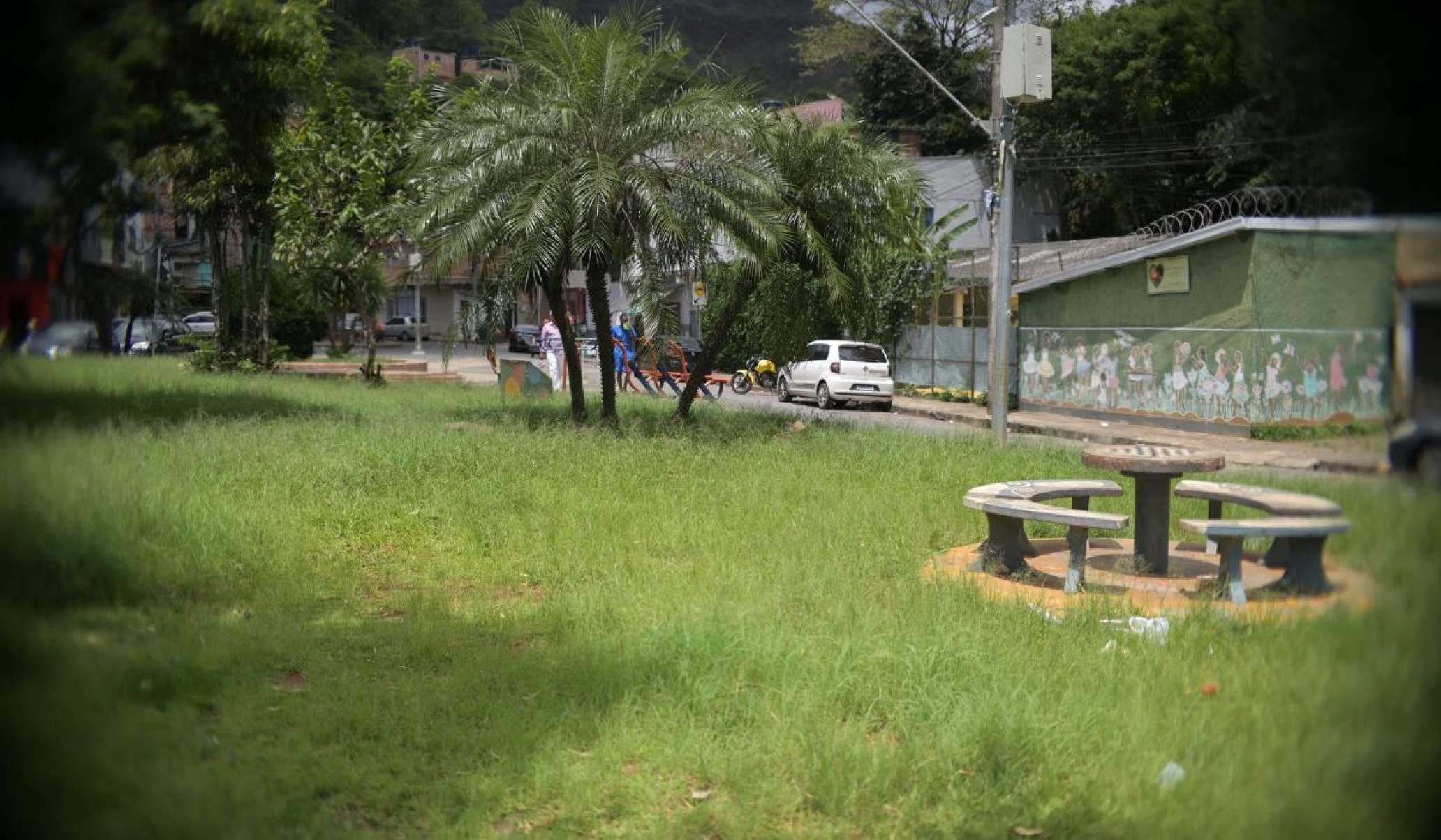 Pra&ccedil;a Carioca, localizada ao lado da Pra&ccedil;a JK precisa de reforma e jardinagem. Imagem mostra o mato alto, com a placa sem tinta e o piso precisando de reformas 