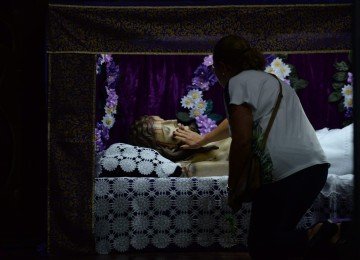 Ao se ajoelhar diante do esquife de Jesus, para uma breve oração ou tocar a imagem, o fiel mantém um velho costume: trocar uma moedinha por outra -  (crédito: Túlio Santos/EM/D.A Press)