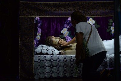 Ao se ajoelhar diante do esquife de Jesus, para uma breve oração ou tocar a imagem, o fiel mantém um velho costume: trocar uma moedinha por outra -  (crédito: Túlio Santos/EM/D.A Press)