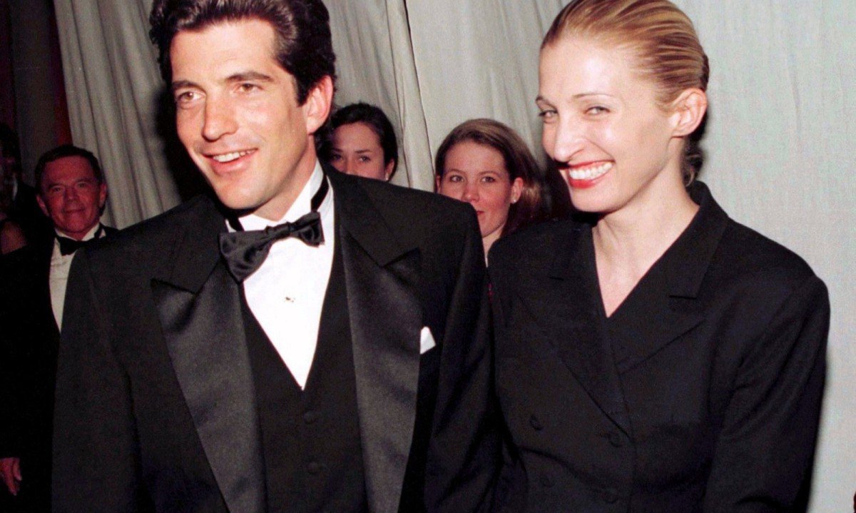 John F. Kennedy Jr e Carolyn Bessette-Kennedy em jantar de gala em Nova York, em 1997. Ele est&aacute; de smoking e ela de roupa preta, sorrindo para a c&acirc;mera