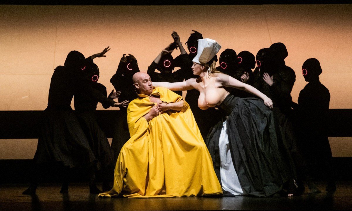 Bailarino usando manto amarelo-ovo tenta se esquivar de bailarina com os seios de fora e saia branca e preta, ao lado dele, no espet&aacute;culo Carmina Burana Ballet, do grupo portugu&ecirc;s Vortice