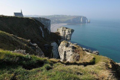Na costa da Normandia, as Falésias de Étretat se erguem como uma das paisagens mais icônicas da França, atraindo visitantes de todo o mundo. O contraste entre o branco imponente das rochas e o azul profundo do mar cria uma atmosfera de contemplação única e inesquecível. Este é o início de uma jornada que une beleza natural, história cultural e inspiração artística. Formadas por calcário branco, as falésias foram moldadas ao longo de milênios pela força do vento e das ondas do Canal da Mancha. Ca -  (crédito: Olivier Dugornay wikimedia commons)