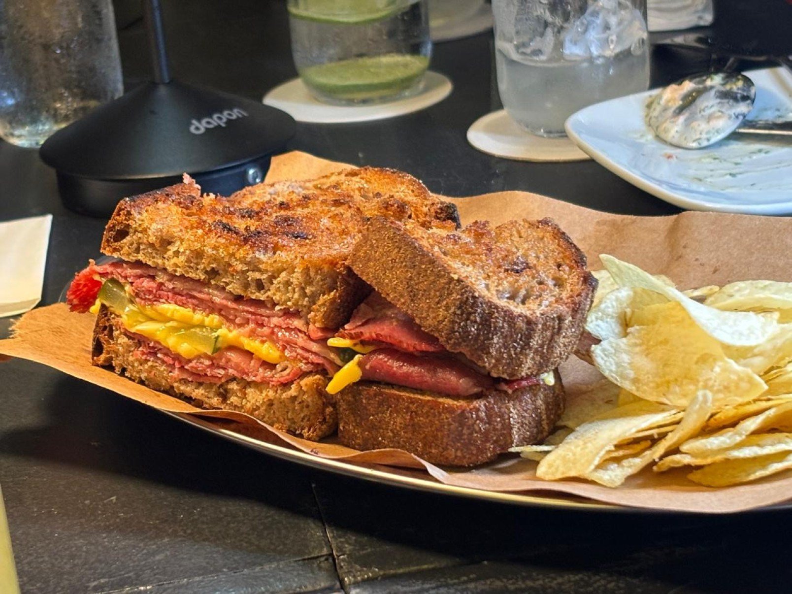 O pastrami da casa recheia um sandu&iacute;che com mostarda, picles e queijo prato