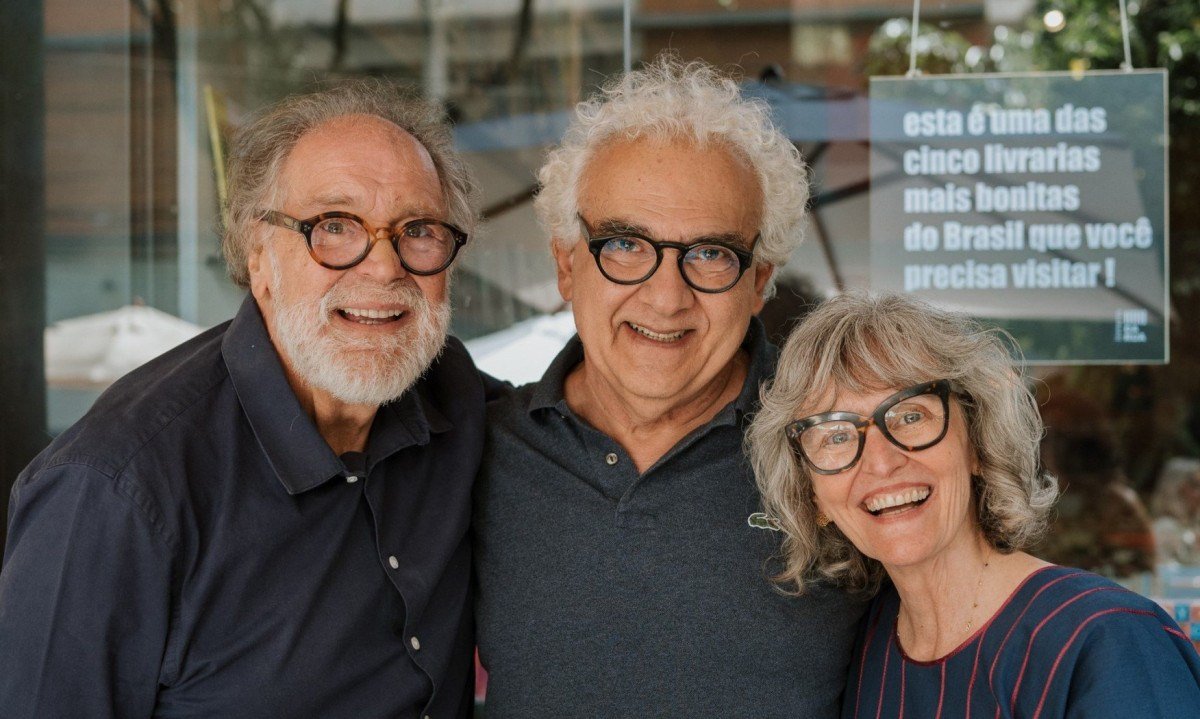 Sorrindo, Gustavo Penna, Milton Hatoum e Fab&iacute;ola Moulin est&atilde;o abra&ccedil;ados em frente &agrave; vitrine da Livraria da Rua, em Belo Horizonte