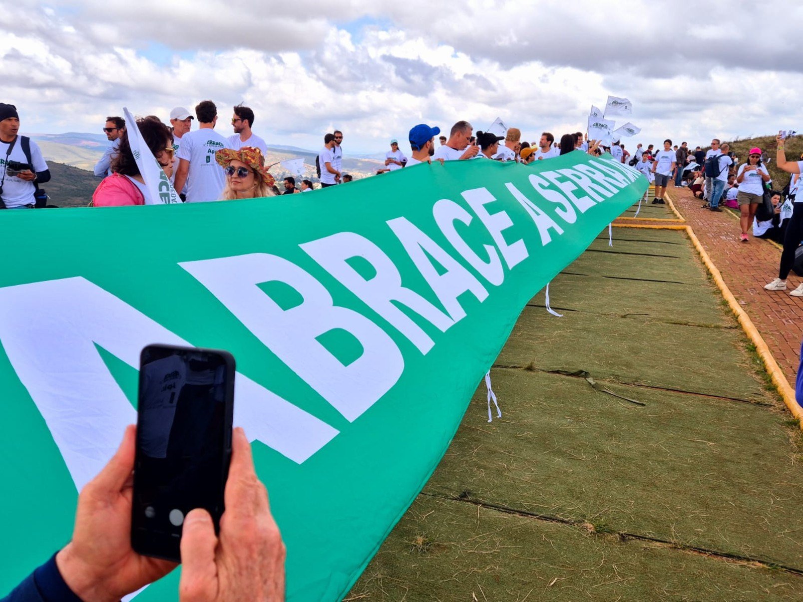 Vestidos com camisetas brancas, os participantes formaram um cord&atilde;o humano no ponto mais alto da serra e estenderam uma grande bandeira