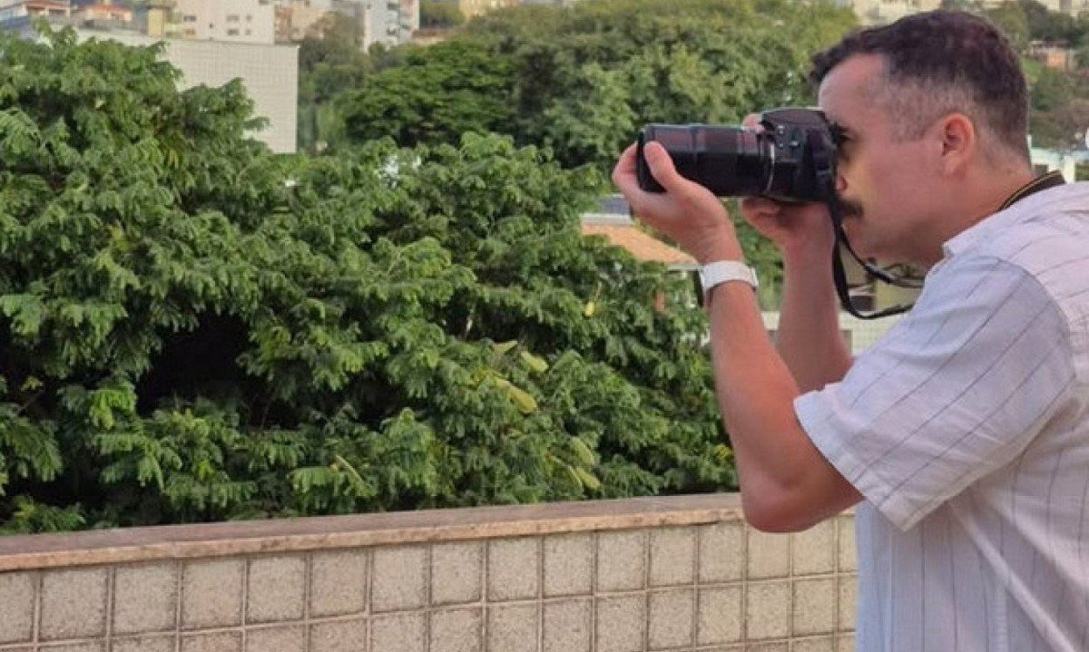 Escritor Ewerton Martins Ribeiro est&aacute; em varanda de apartamento fotografando a cidade