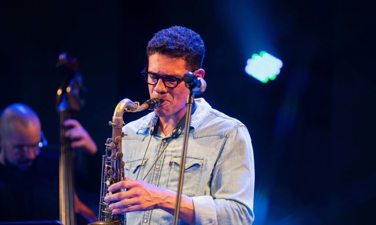 Vinicius Mendes est&aacute; diante de microfone, durante show, e toca saxofone