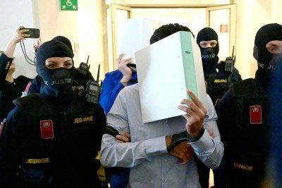 Dois réus algemados são escoltados por agentes da justiça até o tribunal de Wiener Neustadt, na Áustria, em 28 de abril de 2026, para o julgamento de um suposto plano para atacar um show de Taylor Swift em Viena -  (crédito: ROLAND SCHLAGER / APA / AFP)