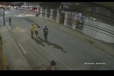 Um dos homens, usando camisa azul, aparece segurando uma barra de ferro enquanto agride a vítima com socos e empurrões. Outro suspeito, utilizando um chapéu de palha, acompanha toda a ação -  (crédito: PMMG/Reprodução)