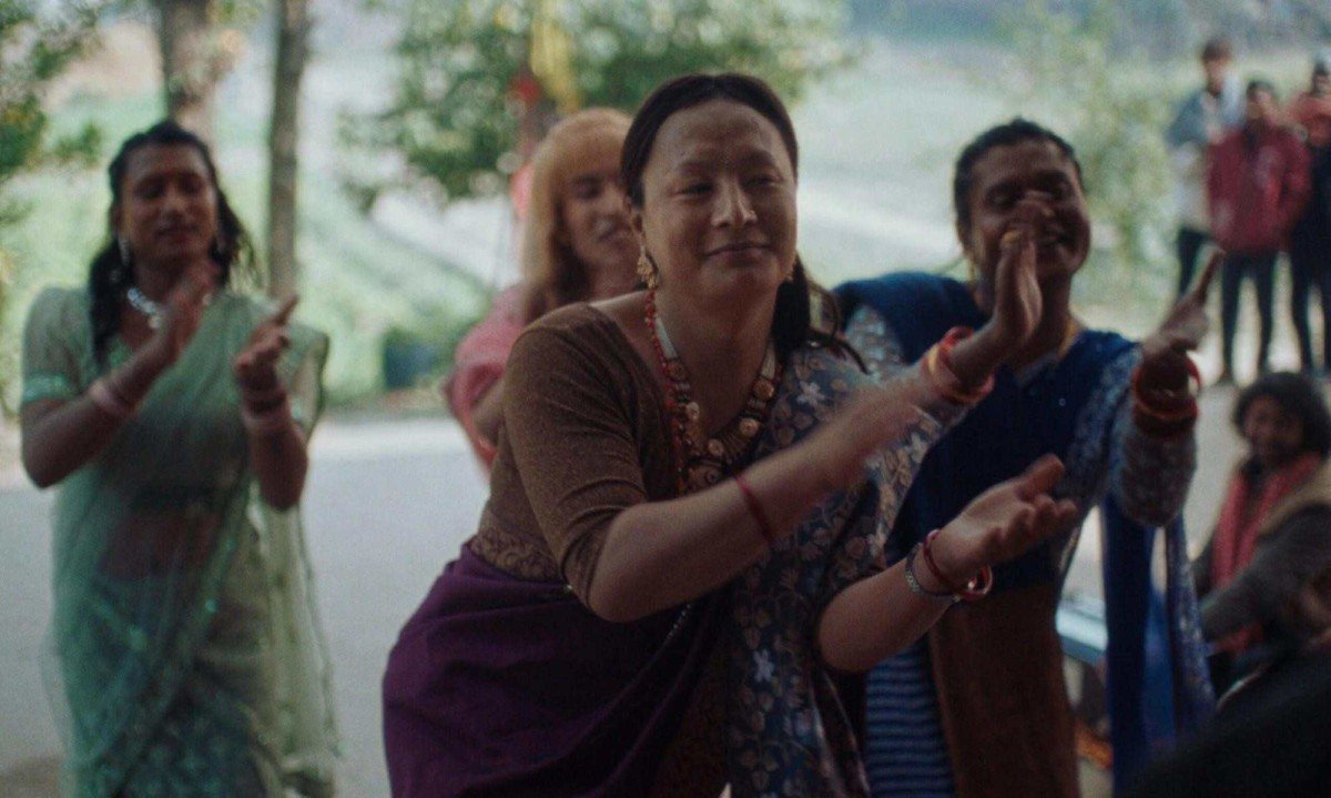 Mulheres do Nepal usando roupas t&iacute;picas daquele pa&iacute;s batem palmas e sorriem em cena do filme Elefantes na n&eacute;voa