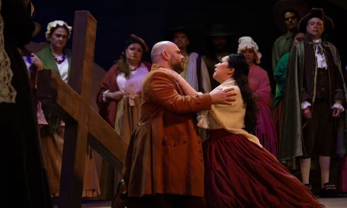 Cantor e cantora l&iacute;rica est&atilde;o abra&ccedil;ados em cena da &oacute;pera Devo&ccedil;&atilde;o